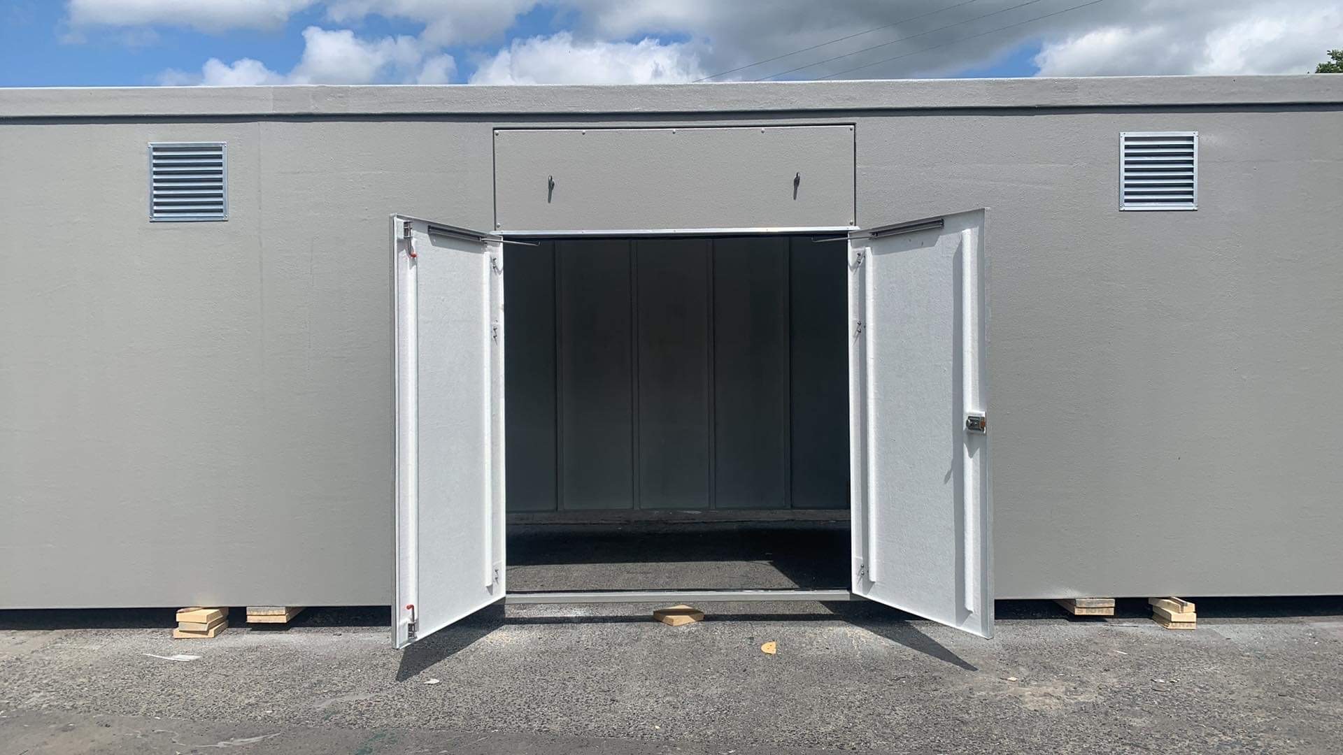 Large grey GRP enclosure with open double doors and ventilation