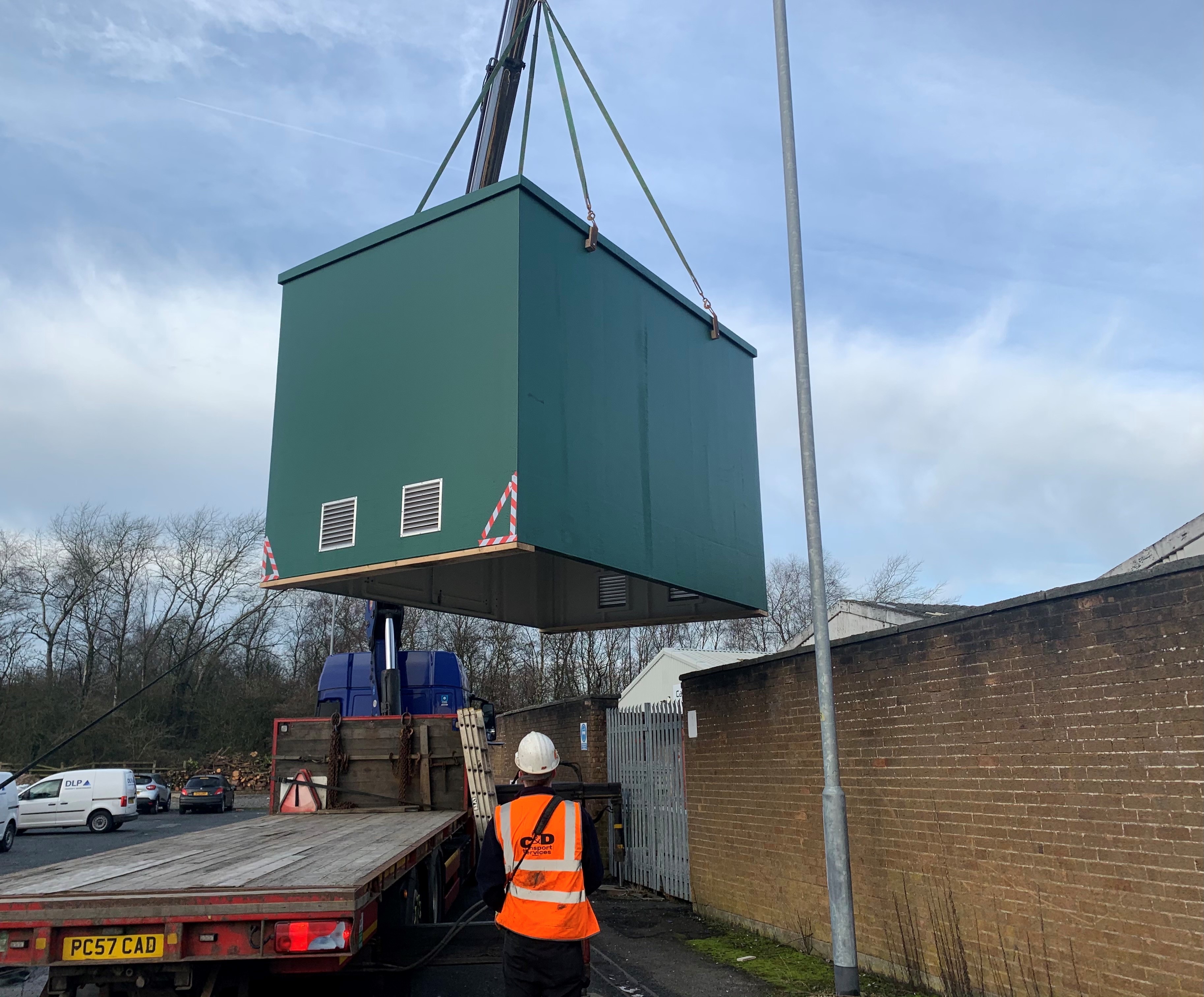 Green GRP kiosk being lifted for delivery