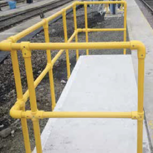Yellow GRP key clamp handrails installed beside a railway platform